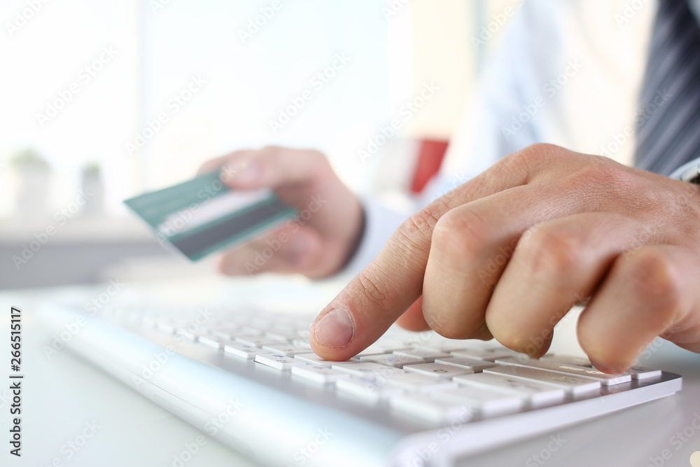 Male arms hold credit card press buttons making transfer closeup. Anti-fraud financial security when entering client discount program number or filling personal credential password login to account Male arms hold credit card press buttons making transfer closeup. Anti-fraud financial security when entering client discount program number or filling personal credential password login to account