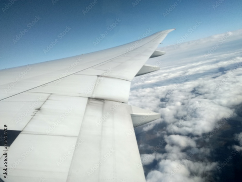 wing of an airplane flying above clouds wing of an airplane flying above clouds