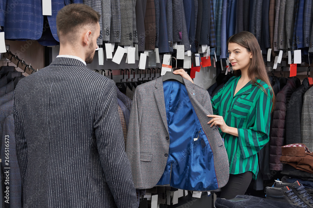 Shop consultant choosing and showing jacket for client. Shop consultant choosing and showing jacket for client.