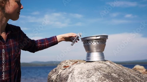 Swedish girl puts on the pan of a Trangia portable stove to cook at the lake. Part three. 60 fps Slowmotion. photo