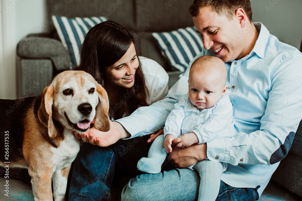 .Beautiful and sweet family playing at home with their little baby and their beagle dog. Children and dogs a relationship of care and love. Lifestyle