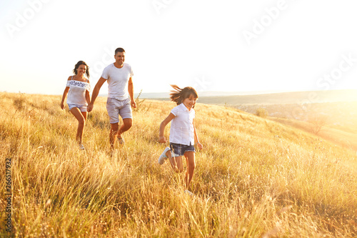 Happy family walking in nature at sunset in summer.