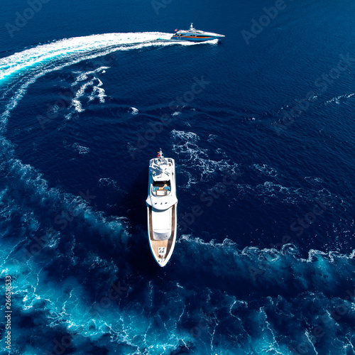 Top view of speed yacht on the sea running around luxury yacht. © LaptevArt