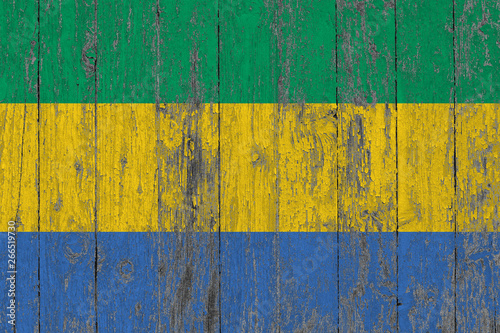 Flag of Gabon painted on worn out wooden texture background.