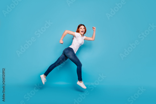 Full length body size profile side view portrait of her she nice attractive cheerful cheery strong girl wearing white tshirt fast speed isolated over bright vivid shine blue background