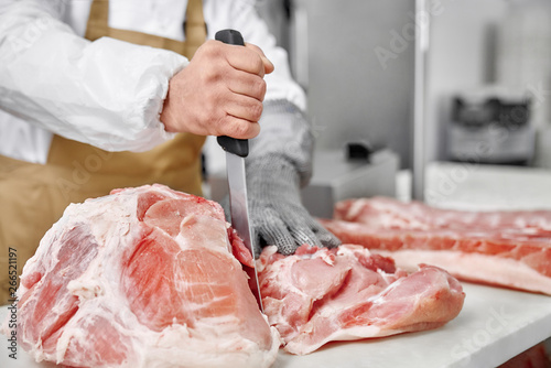 Obraz na plátně Close up of raw meat and butcher cutting meat with knife.