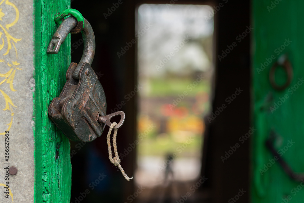 Old scratched lock hanging on the green door. The key is inserted into the lock. Canon EOS 77D, f/3.2, ISO100, 1/320. Noon. Marino. Michurinsk. Old scratched lock hanging on the green door. The key is inserted into the lock. Canon EOS 77D, f/3.2, ISO100, 1/320. Noon. Marino. Michurinsk.