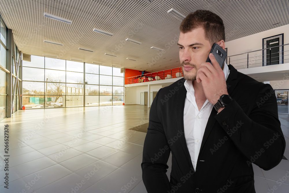 Beautiful serious business man in suit with smartphone in modern office Beautiful serious business man in suit with smartphone in modern office