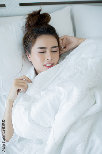Beautiful young woman lying down in the bed and sleeping.