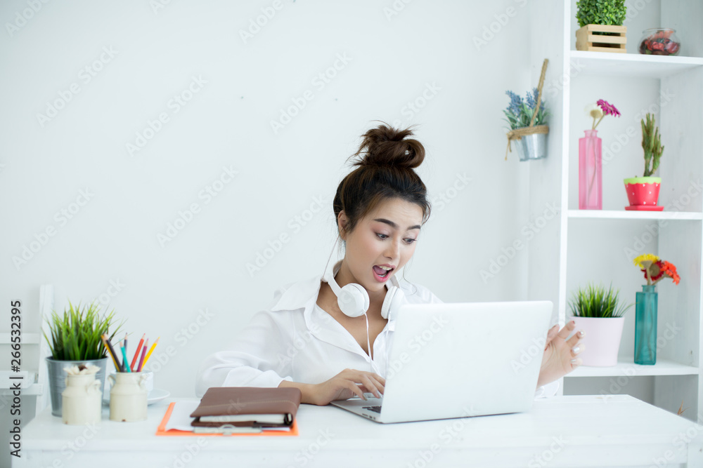 Beautiful young woman working on her laptop in her room. Beautiful young woman working on her laptop in her room.