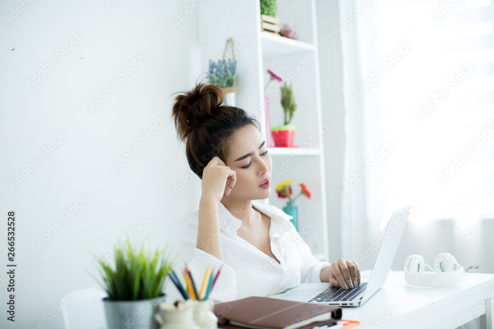 Beautiful young woman working on her laptop in her room. Beautiful young woman working on her laptop in her room.
