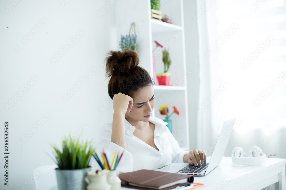 Beautiful young woman working on her laptop in her room. Beautiful young woman working on her laptop in her room.