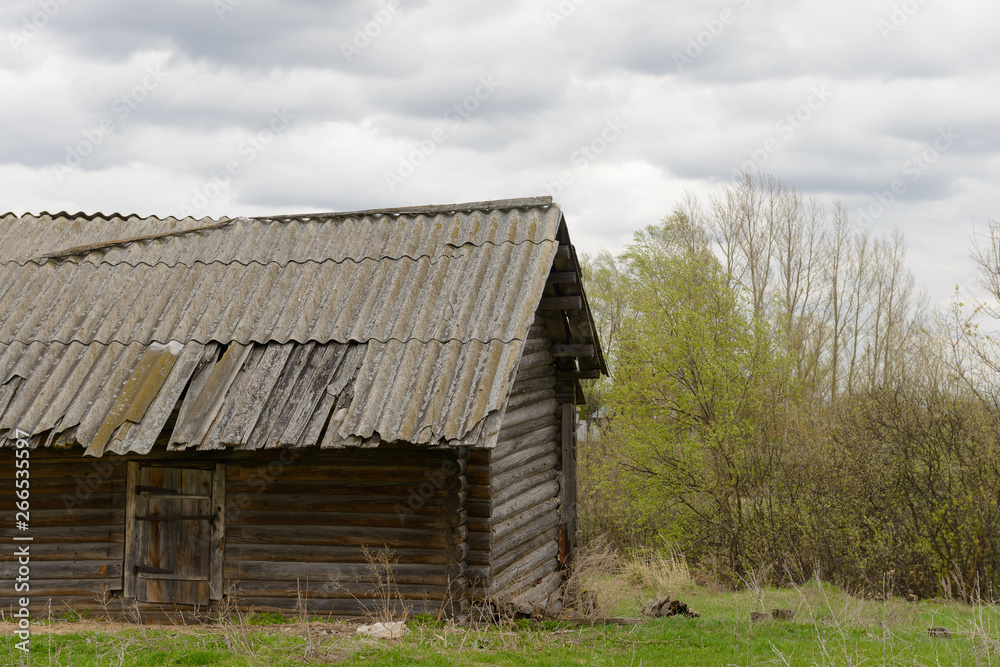 Old abandoned log house among the trees in cloudy weather Old abandoned log house among the trees in cloudy weather