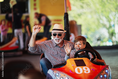 Fotografiet Grandfather and grandson having fun and spending good quality time together in amusement park