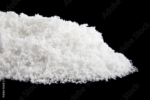A pile of white snow isolated on a black background close-up.