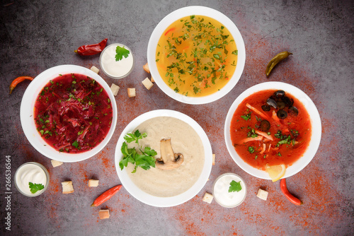 Set of soups from worldwide cuisines, healthy food. Cream soup with mushrooms,solyanka, russian borscht, chicken soup on silver background. Top view.