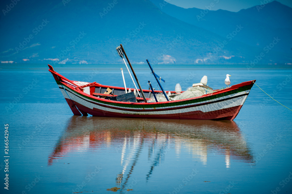 Barco de pesca com reflexo e céu azul Barco de pesca com reflexo e céu azul