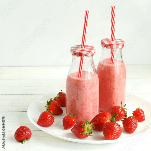 Strawberry smoothie or milkshake in a glass on white wooden background. Healthy food for breakfast and snack. 