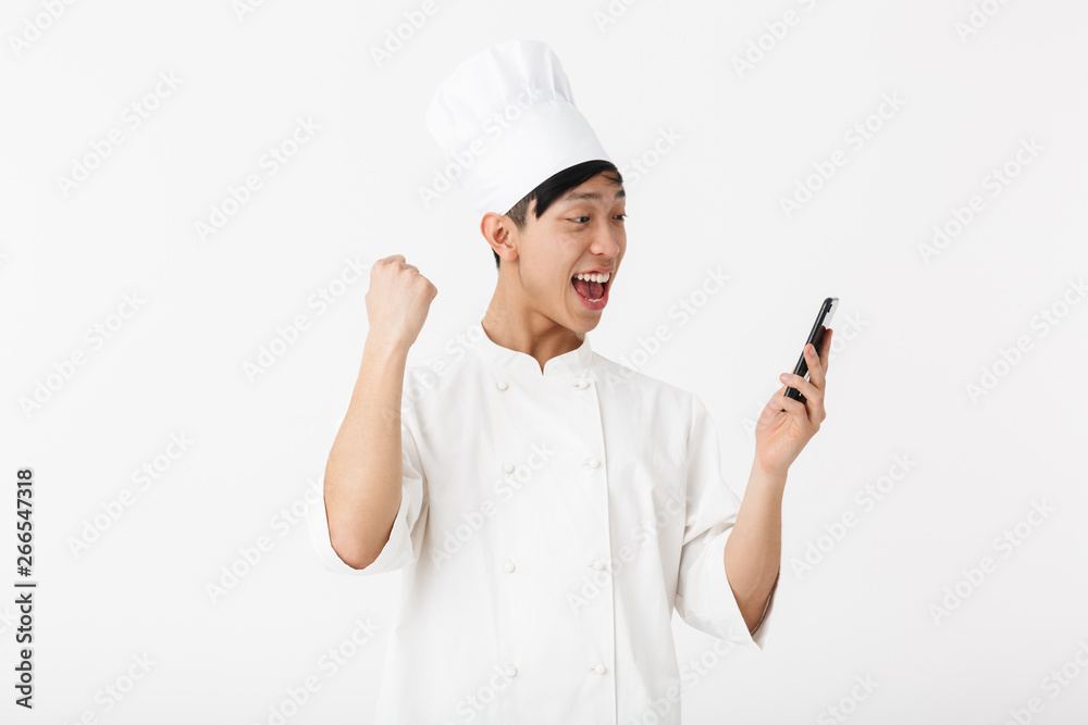 Image of successful chinese chief man in white cook uniform and chef's hat holding mobile phone Image of successful chinese chief man in white cook uniform and chef's hat holding mobile phone