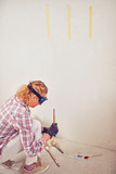 Working woman plastering / painting walls inside the house.