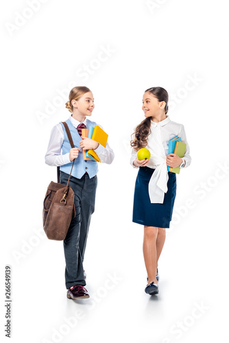schoolgirls in formal wear with apple and books looking at each other and talking On White