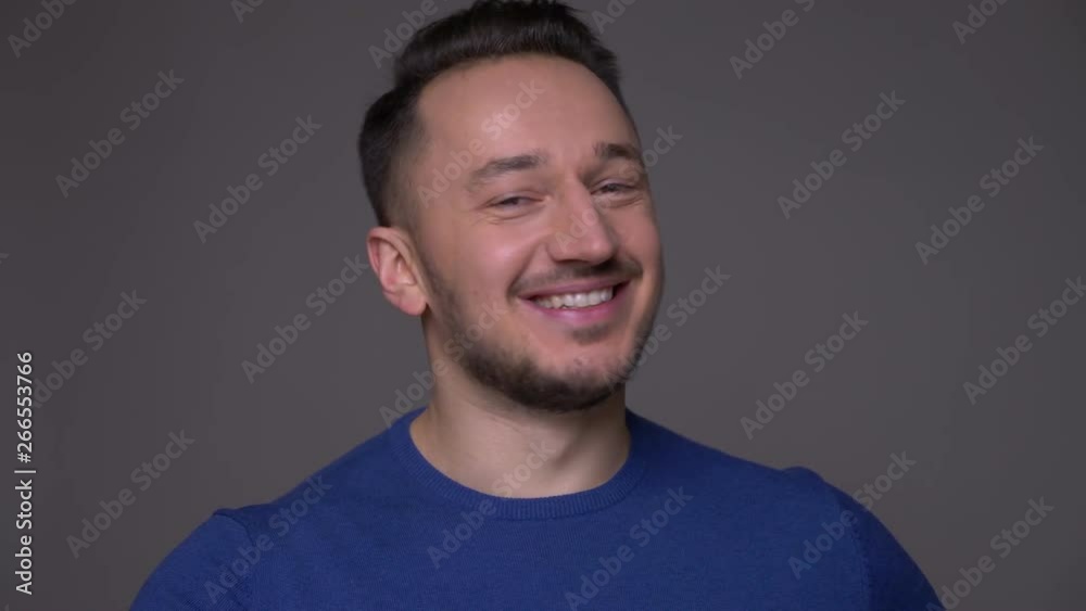 Closeup shoot of young handsome caucasian man smiling with excitement looking at camera with background isolated on gray Closeup shoot of young handsome caucasian man smiling with excitement looking at camera with background isolated on gray