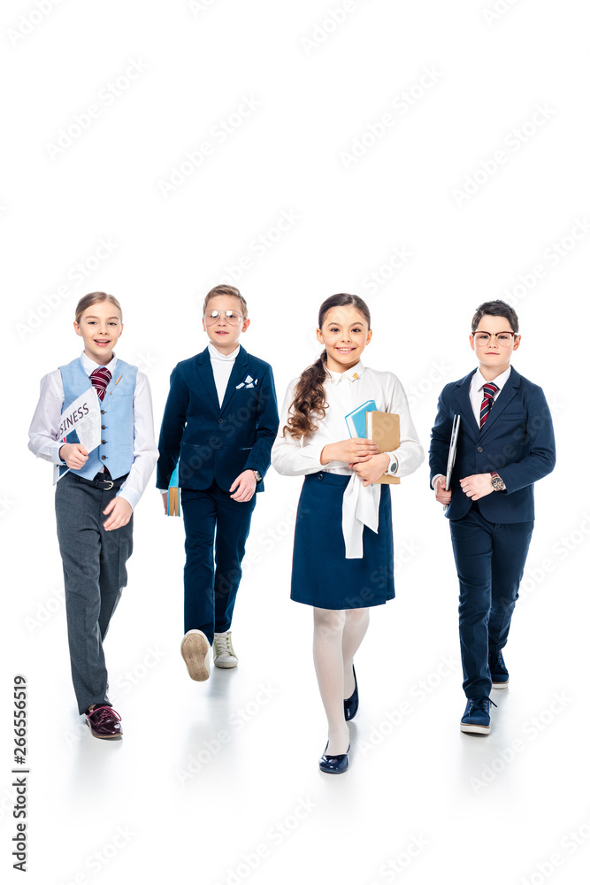 schoolchildren pretending to be businesspeople with books and newspaper walking On White schoolchildren pretending to be businesspeople with books and newspaper walking On White