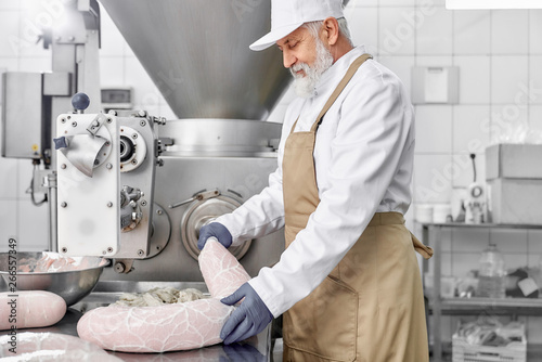 Obraz na plátně Man working with equipment for production sassages.