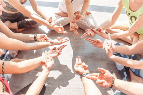 Group of young people doing mudra sit in a lotus position in a circle In the bright gym during meditation. Group yoga concept photo