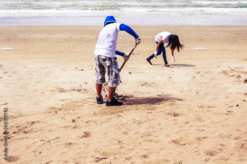 man and woman are helping to clean up beaches on the sunsat photo