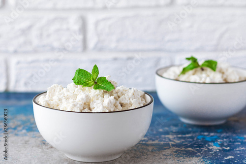 Cottage cheese with mint leaves on a light background in white bowl