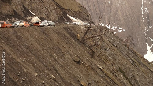 Medium low-angle still shot of vehicles passing each other along the dangerous Zoji La, Ladakh. Glacier flow to the road from an ar te forces vehicles from one side to give way, Ladakh 