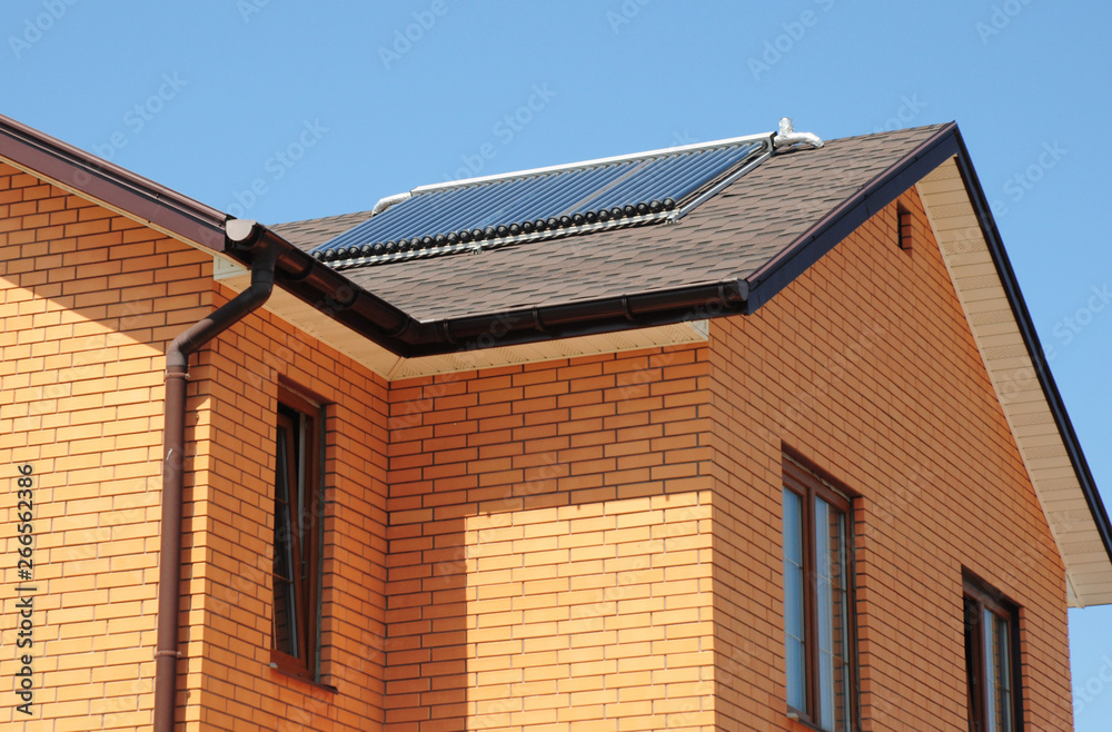 Brick house asphalt shingles roof top with solar water heater, solar water heating panels .