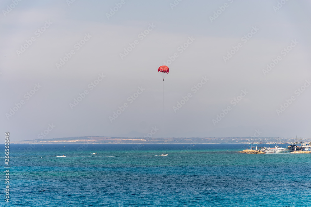 CYPRUS, AYIA NAPA - MAY 11/2018: tourists have fun on a parachute over the Mediterranean Sea near the seaport. CYPRUS, AYIA NAPA - MAY 11/2018: tourists have fun on a parachute over the Mediterranean Sea near the seaport.