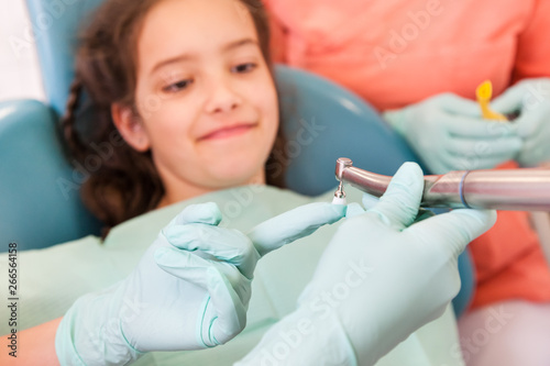 Pretty girl at the dentist who is showing an instrument