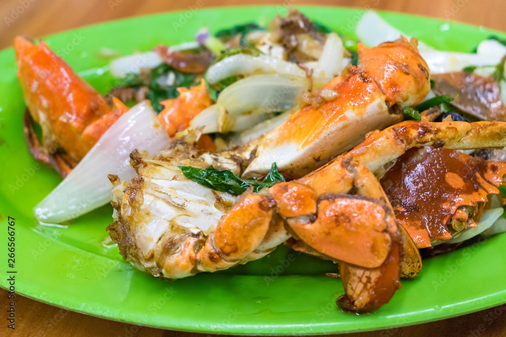 Fried red crab in tasty sauce with green salad on green plate