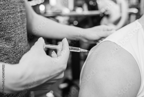 Doctor makes an injection to her boyfriend in gym