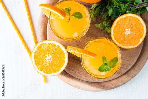 Close-up of a glass of orange juice with oranges fruits on wooden and stone background. Vitamins and minerals. Healthy drink and beverage concept.