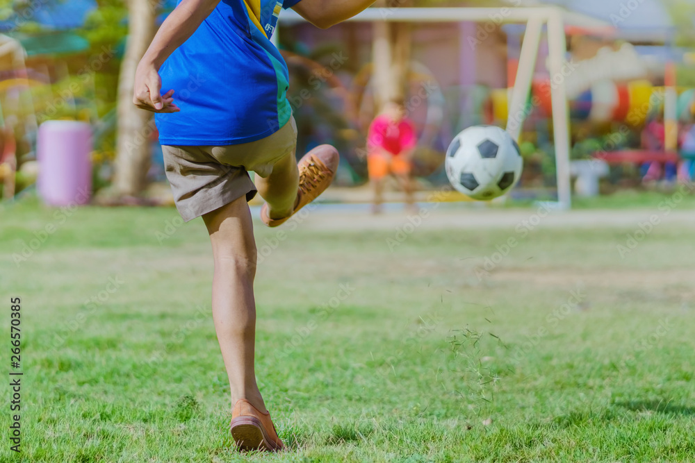 Asian boys practice kicking the ball to score goals in the public football field. Asian boys practice kicking the ball to score goals in the public football field.
