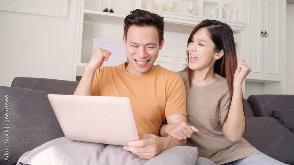 Asian couple using laptop for search web in living room at home, sweet couple enjoy love moment while lying on the sofa when relax at home. Lifestyle couple relax at home concept. Asian couple using laptop for search web in living room at home, sweet couple enjoy love moment while lying on the sofa when relax at home. Lifestyle couple relax at home concept.