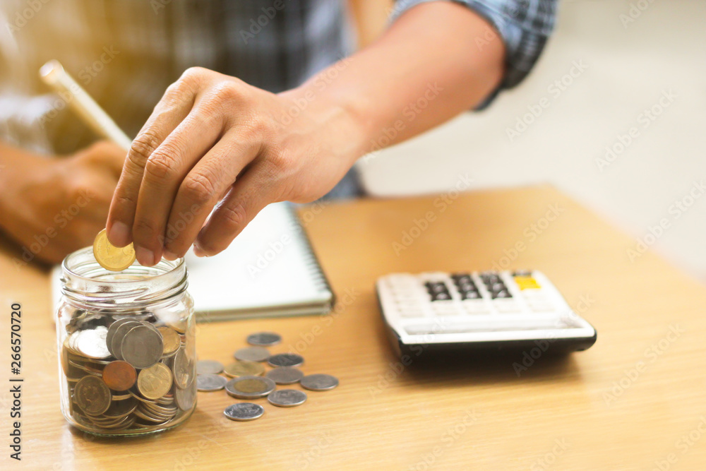 A businessman holding coins putting into the glass. concept saving money and finance accounting. A businessman holding coins putting into the glass. concept saving money and finance accounting.