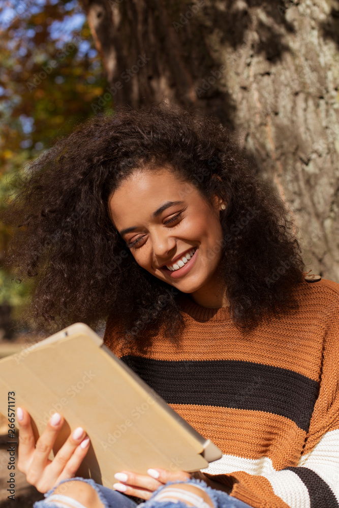 Beautiful young girl with dark curly hair using tablet computer, outdoor. Beautiful young girl with dark curly hair using tablet computer, outdoor.