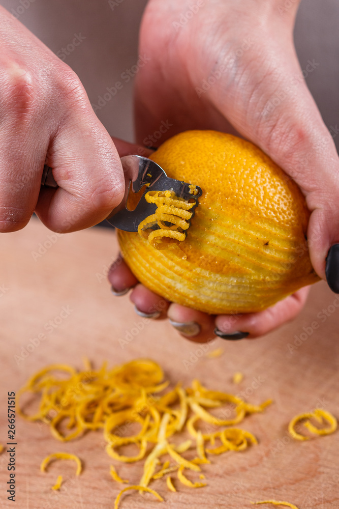 young woman in a gray aprons cuts lemon zest young woman in a gray aprons cuts lemon zest