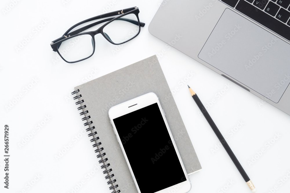 Creative flat lay photo of workspace desk. Top view office desk with laptop, blank phone, pencil, notebook and glasses on white color background. Top view with copy space, flat lay photography. Creative flat lay photo of workspace desk. Top view office desk with laptop, blank phone, pencil, notebook and glasses on white color background. Top view with copy space, flat lay photography.