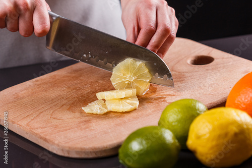 young woman in a gray aprons cut lemon