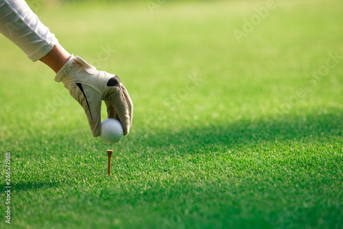 Close up on woman golfer hand putting golf ball on tee at golf course ,Healthy Holiday Concept