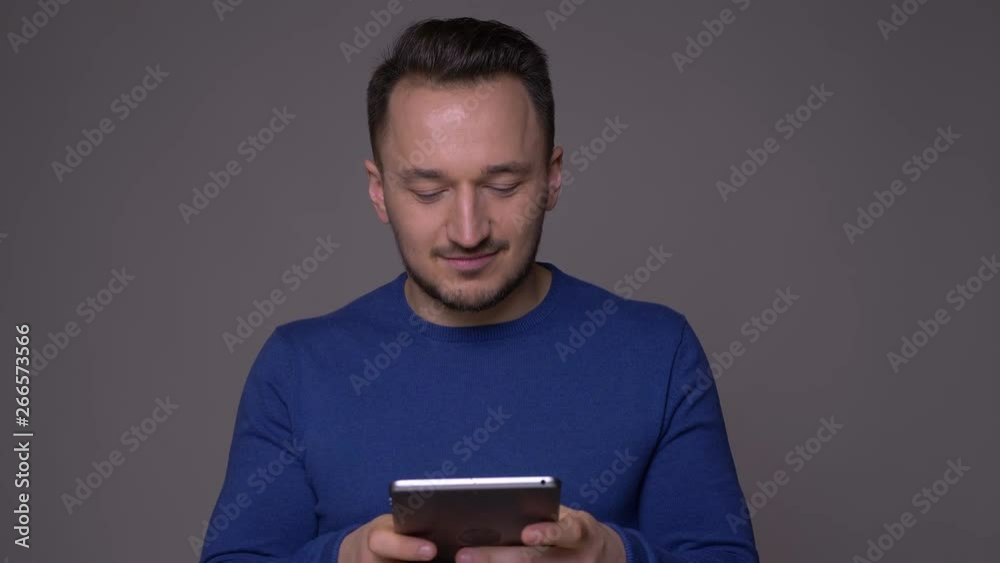 Closeup shoot of young handsome caucasian man using the tablet with background isolated on gray