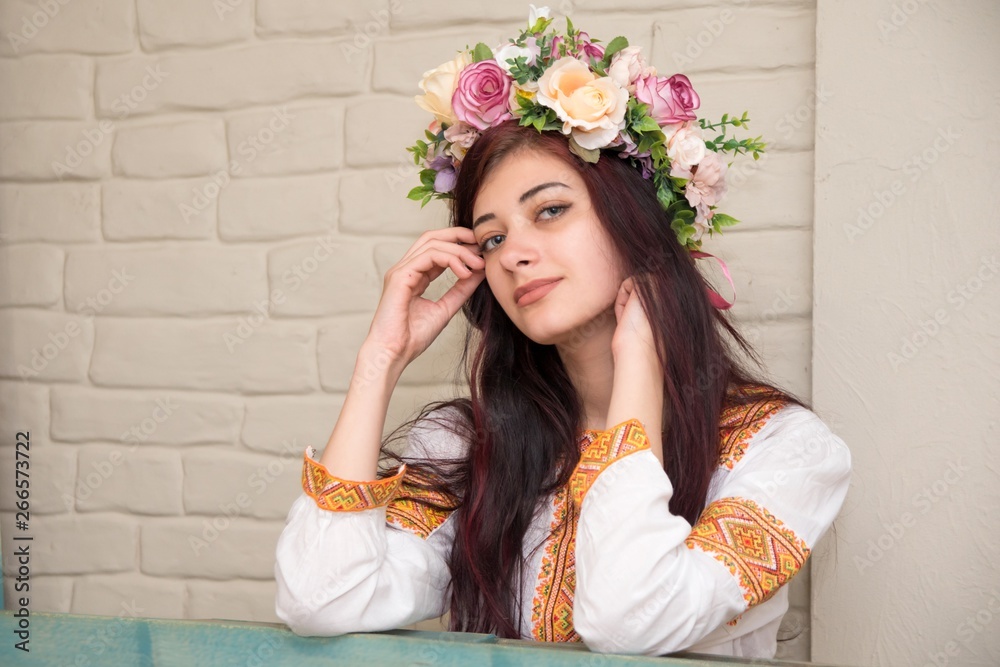Portrait of a girl in an embroidered shirt and with a wreath on his head. Wreath is a traditional Ukrainian girl's headgear. Embroidered shirt - traditional Ukrainian clothes.