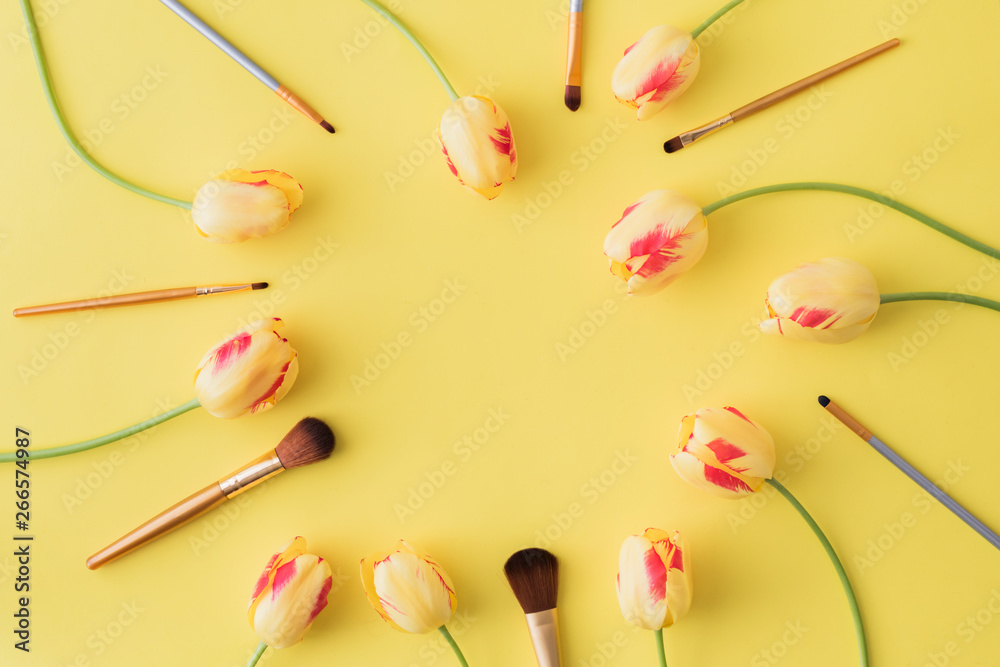 Flat lay composition with cosmetic products for makeup and yellow tulips on a yellow background Flat lay composition with cosmetic products for makeup and yellow tulips on a yellow background