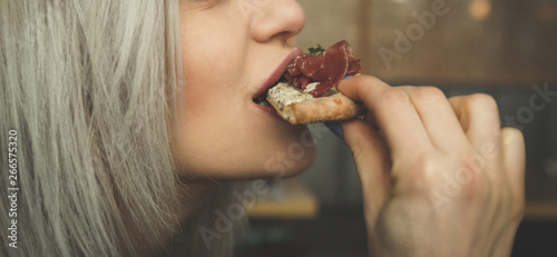 Beautiful young girl eats a slice of pizza in a cafe - Portrait of a beautiful girl eats.